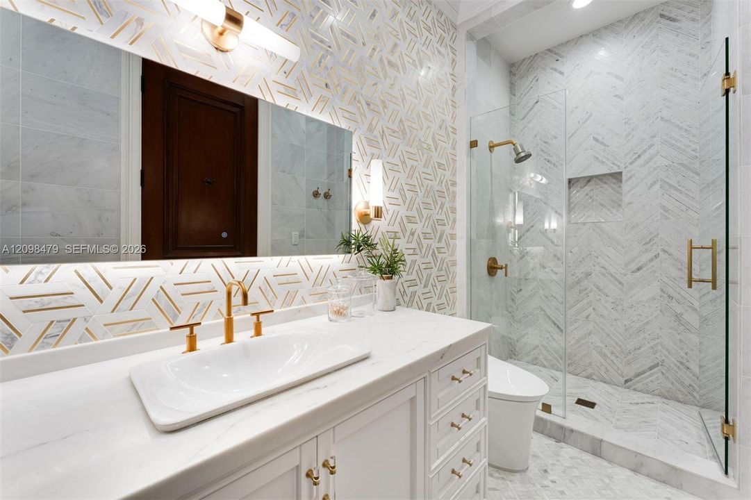 White vanity with gold hardware, a rectangular vessel sink, and gold-finish faucet