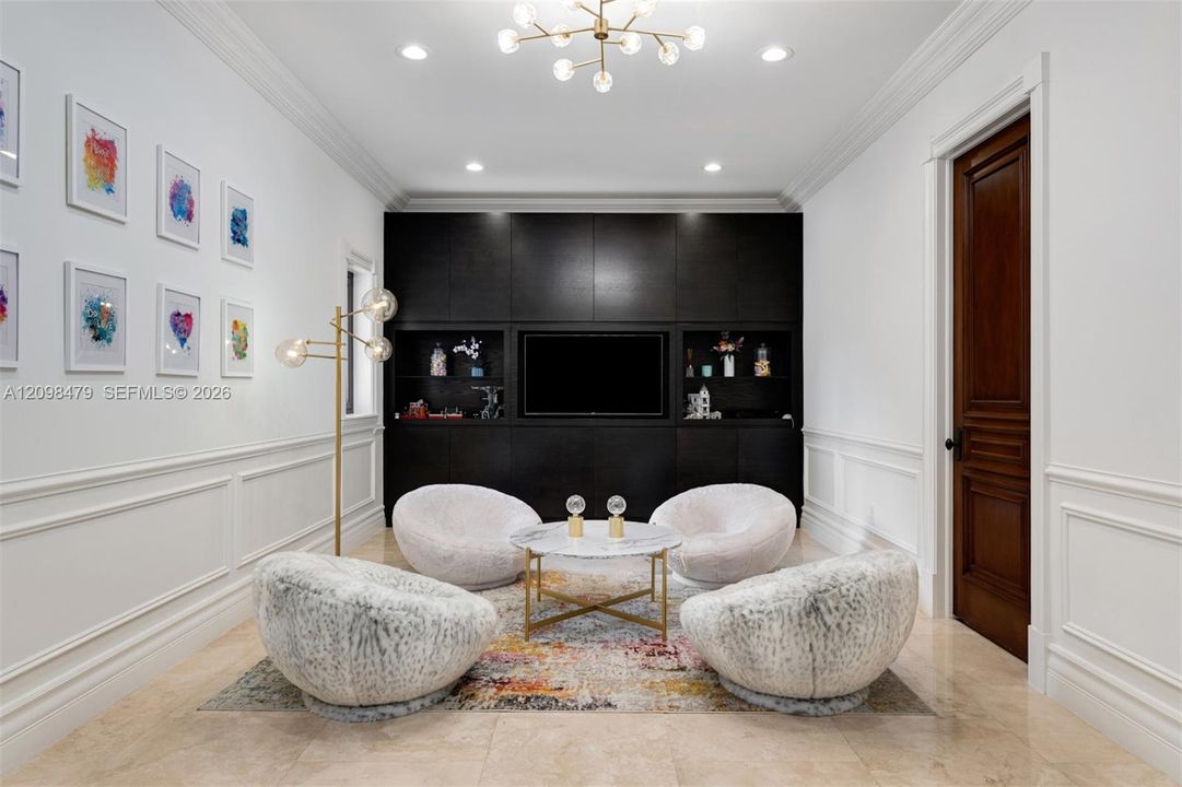 Recessed lighting with a modern chandelier, dark wood-finish built-in cabinetry, elegant wainscoting, and large format tile flooring