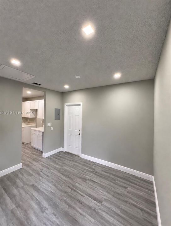 Neutral-toned interior featuring wood-finish flooring, recessed lighting, and a six-panel door