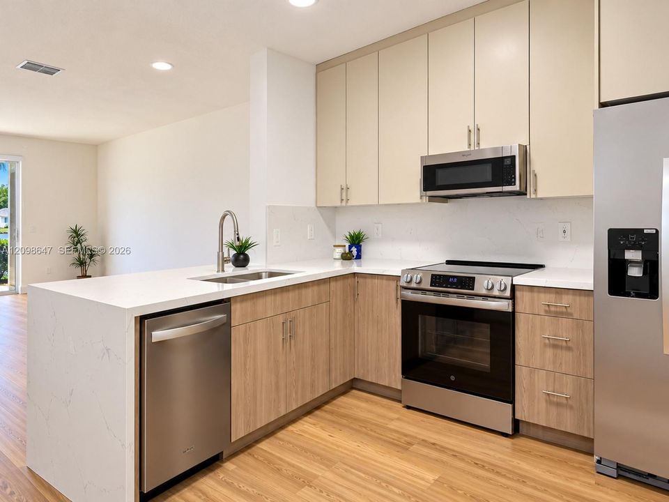 Fully renovated open kitchen featuring brand-new custom cabinetry, stunning Carrara quartz countertops, and stainless steel appliances.