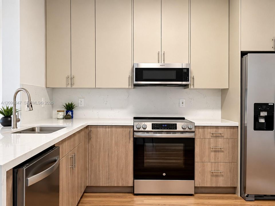 Modern kitchen layout with elegant Carrara quartz surfaces, matching tile backsplash, and generous cabinet storage space.