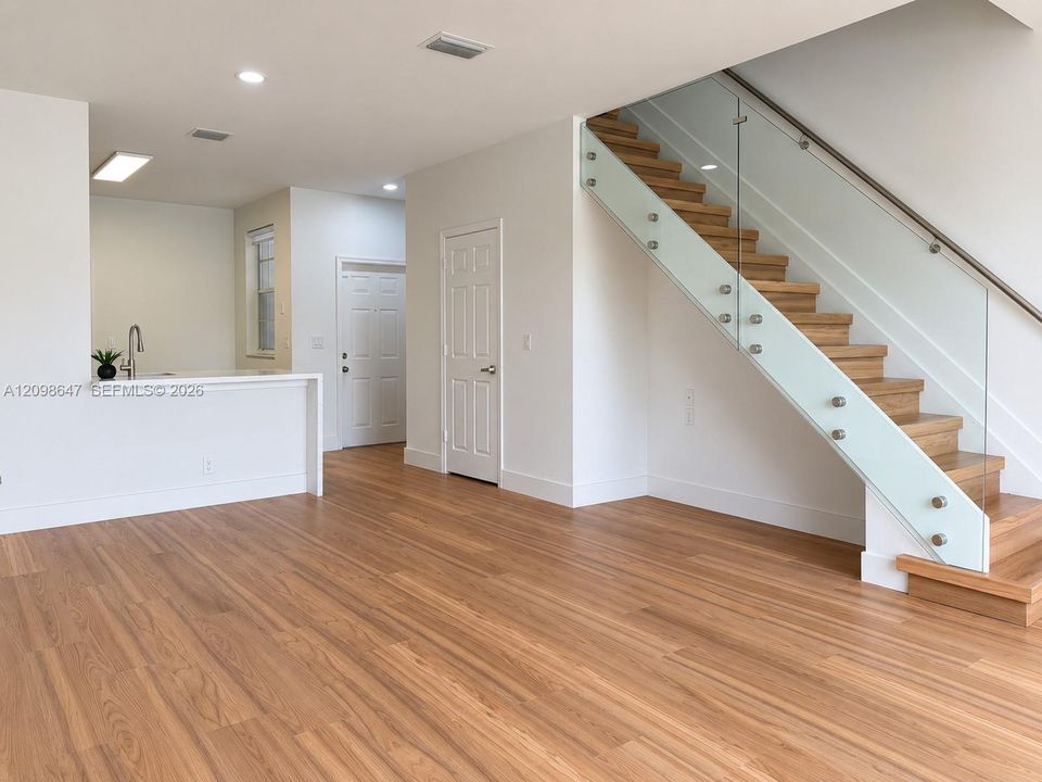 Open living space showcasing clean flooring, high ceilings, and smooth access to the second level.