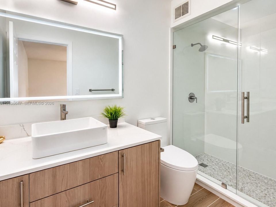 Brand-new full bathroom featuring custom frameless glass shower, sleek modern vanity, and premium updated fixtures.