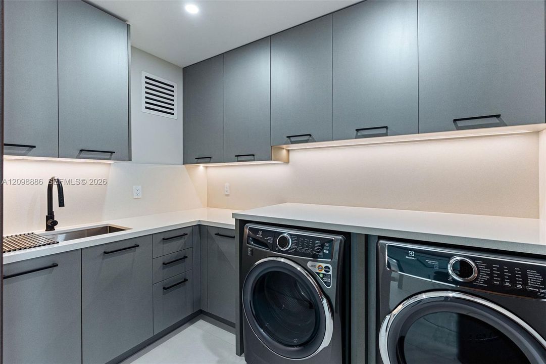 Modern cabinetry with matte hardware, light-toned countertop, undermount sink with a matte black faucet, and under-cabinet integrated lighting