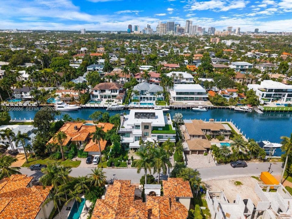Aerial perspective of waterfront property featuring deep-water canal access, private boat dockage, and a multi-level structure with roof terrace and flat-roof architecture