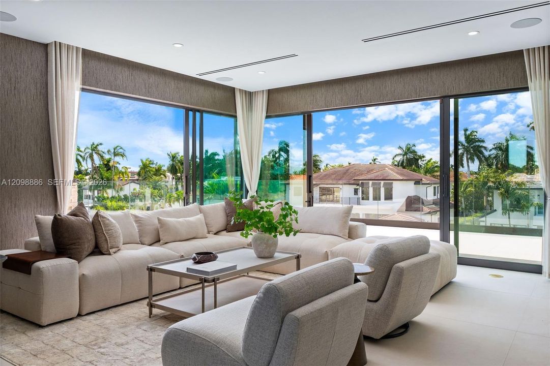 Floor-to-ceiling glass corner walls with multi-panel sliding doors, recessed linear lighting, and large-format tile flooring