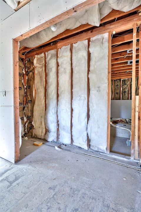 Interior space featuring exposed wood framing, installed fiberglass batt insulation, and unfinished wall surfaces