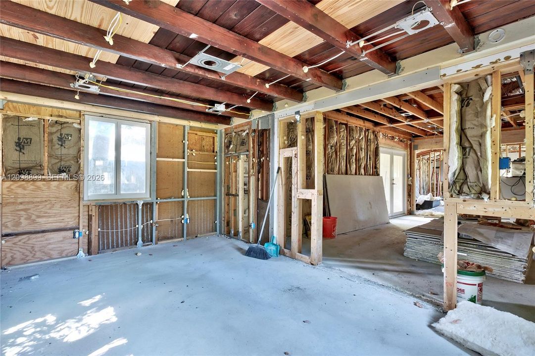 Interior space featuring exposed wood-beam ceiling, concrete flooring, and an exterior window with glass panes
