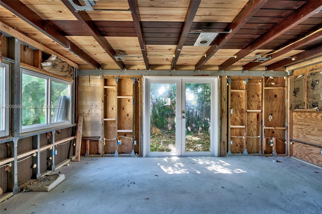 Exposed wood-beam ceiling, glass-paned double doors, dual-pane windows, and concrete flooring