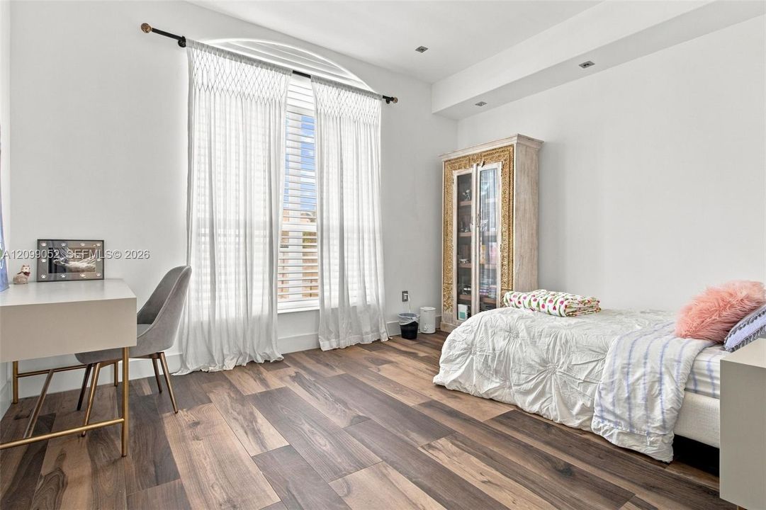 Arched window featuring floor-to-ceiling drapery and wood-finish flooring with recessed ceiling lighting