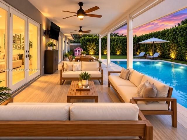 Covered patio featuring wood-finish flooring, dual ceiling fans, recessed wall lighting, and swimming pool with integrated hardscaping