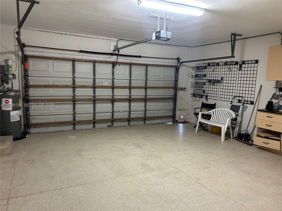 Garage featuring a sectional overhead door, epoxy-coated concrete flooring, built-in storage cabinetry, and wall-mounted organization panels