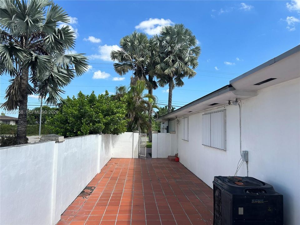 Private exterior courtyard featuring terracotta tile flooring, smooth stucco wall enclosure, and integrated metal gate