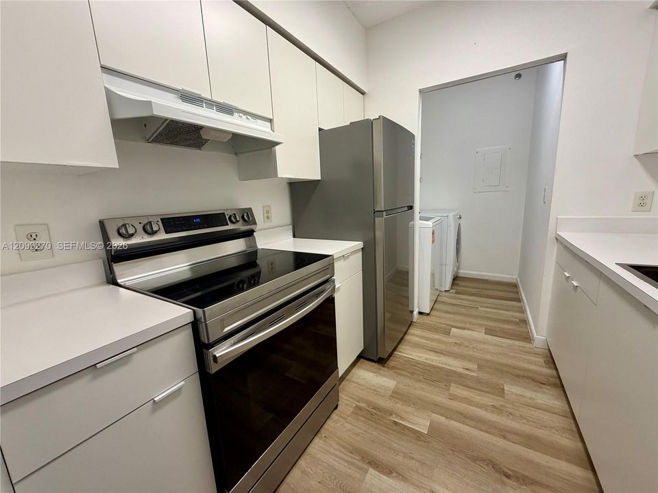 Kitchen featuring white cabinetry, solid-surface countertops, stainless steel appliances, and wood-finish flooring