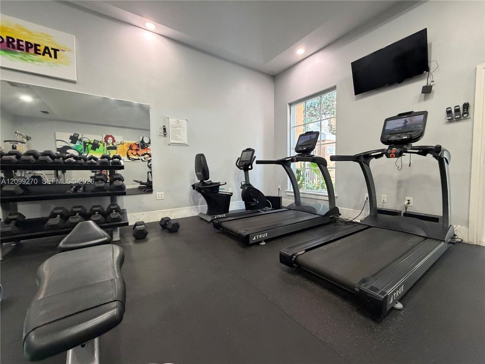 Fitness area featuring recessed ceiling lighting, a large wall-mounted mirror, and durable rubberized flooring