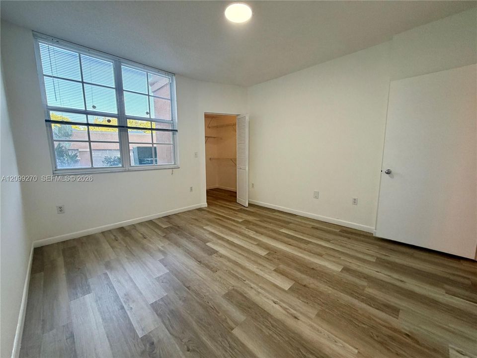 Wood-finish flooring, multi-pane window with natural light, and walk-in closet with built-in shelving