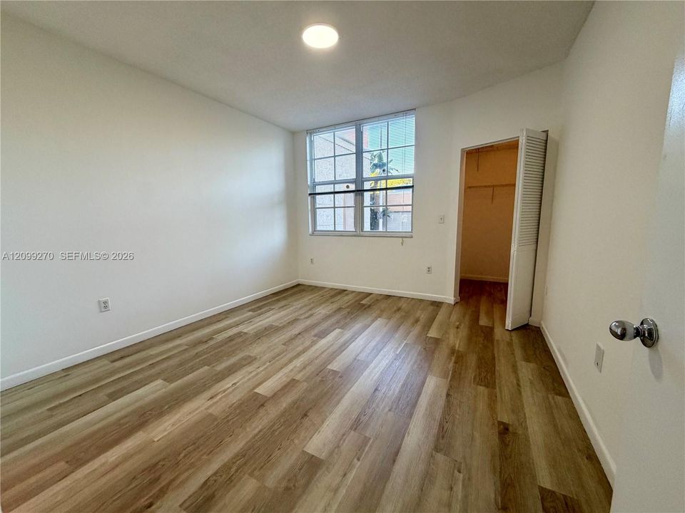 Wood-finish flooring, multi-pane window with grid pattern, and built-in closet with louvered door
