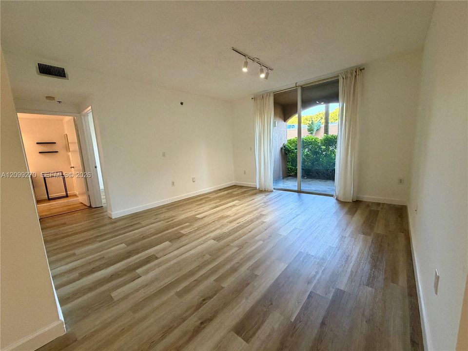 Living space featuring wood-finish flooring, adjustable track lighting, and sliding glass doors opening to a covered patio
