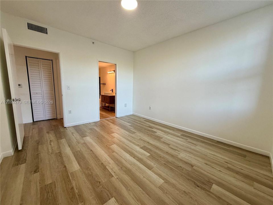 Room featuring wood-finish flooring, white walls, and a closet with louvered doors