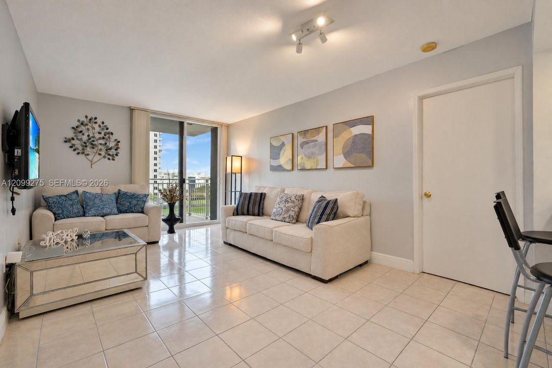Bright, inviting living room with tile flooring and sliding glass doors opening to a private balcony.