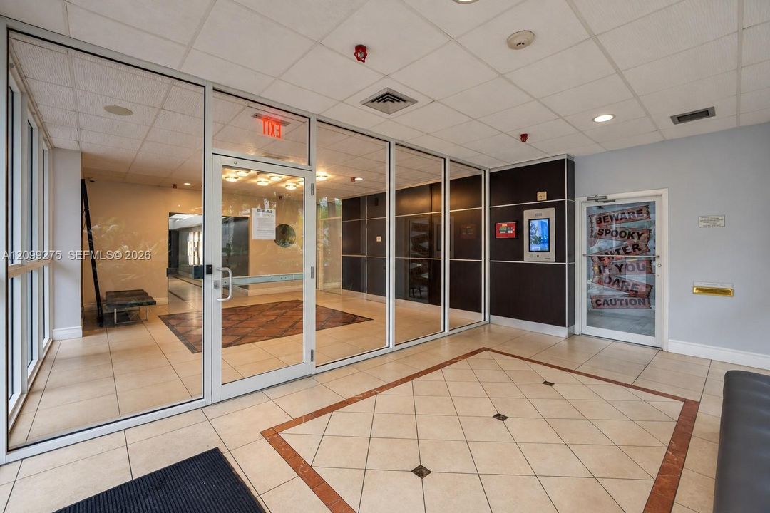 Secure building entrance featuring glass doors, a spacious tiled foyer, and a modern access control system.