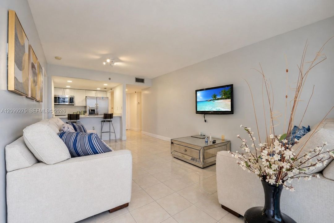 Spacious open-concept living area with elegant tile flooring, and a seamless flow into the kitchen with stainless steel appliances.