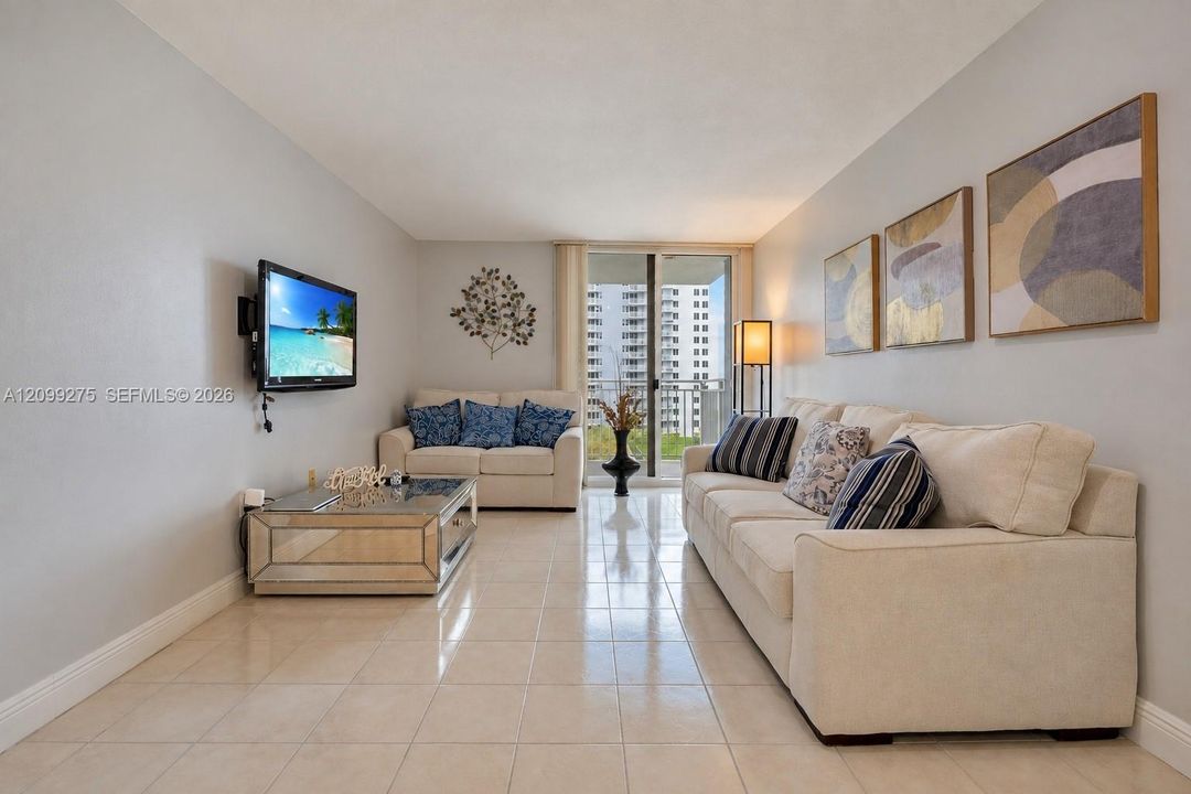 Bright and inviting living room featuring neutral tones, and sliding glass doors opening to a private balcony.