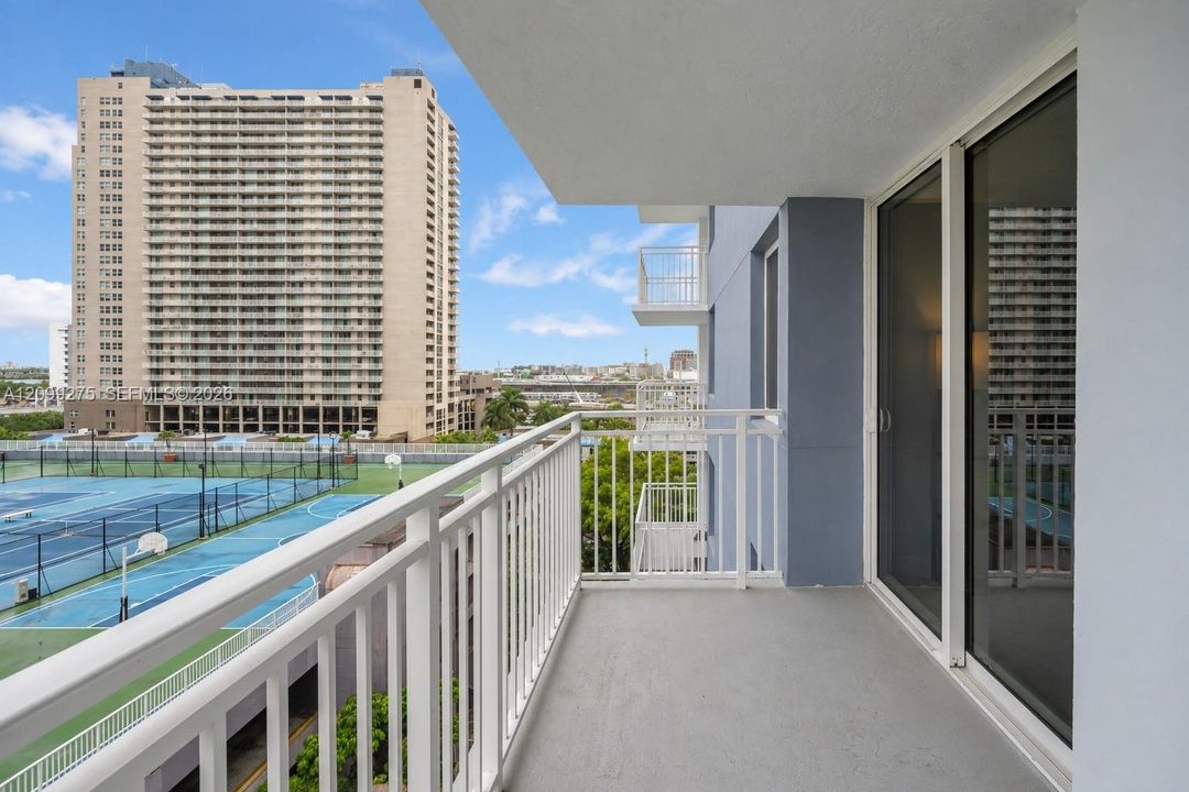 Spacious private balcony featuring white railings and expansive city views, offering an ideal spot to relax and enjoy the open-air setting.