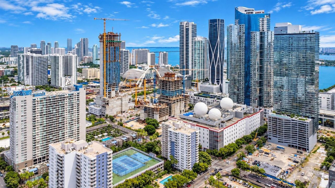 Stunning aerial view of Miami’s vibrant skyline, showcasing modern high-rise towers, Biscayne Bay, and ongoing urban development in a dynamic waterfront setting.