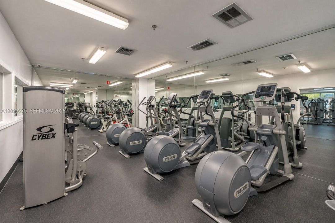 Fully equipped fitness center featuring a wide selection of cardio machines, including elliptical trainers, along with mirrored walls and modern exercise equipment for a convenient indoor workout experience.