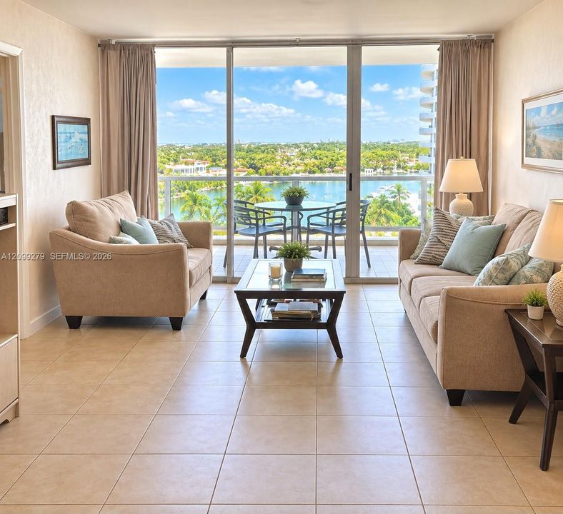 Full-height glass sliding doors, ceramic tile flooring, and a private balcony featuring a metal railing with a water backdrop