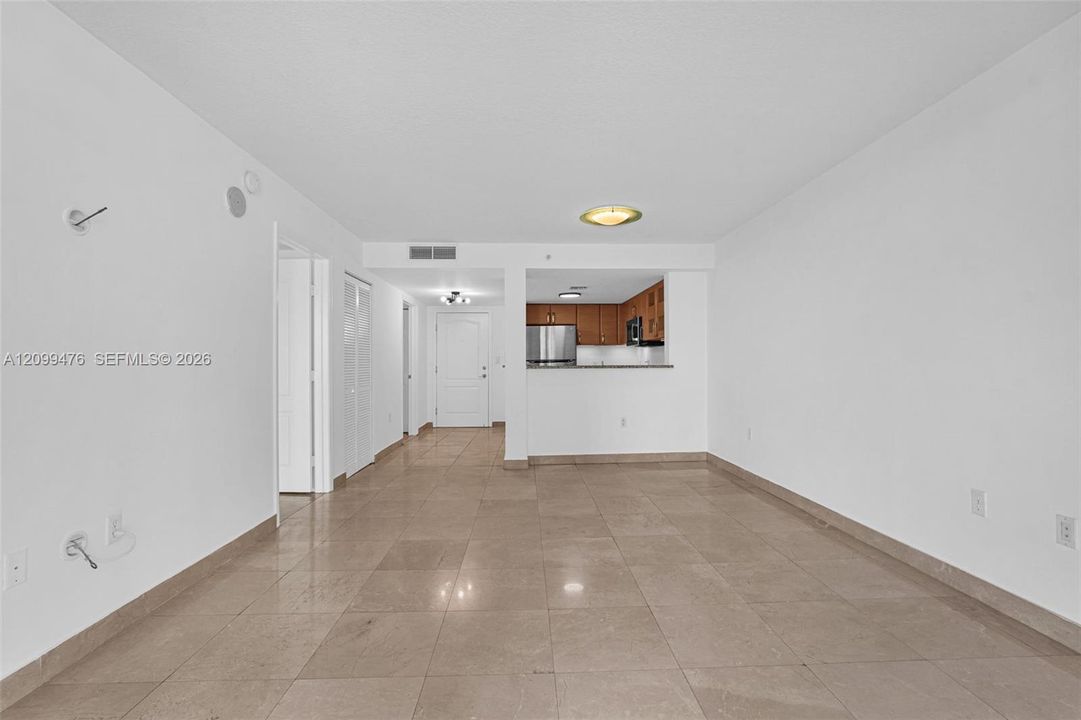 Neutral-toned tile flooring, pass-through kitchen counter, stainless steel refrigerator, and recessed ceiling lighting
