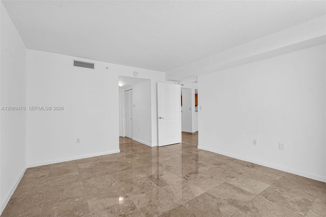 Neutral interior space featuring polished stone flooring, solid-core interior doors, and clean, white-painted wall finishes
