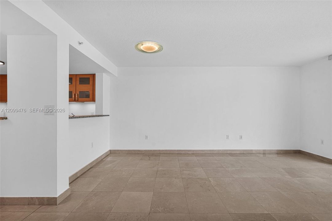 Large-format tile flooring, recessed ceiling lighting, and a breakfast bar with stone-finish countertop