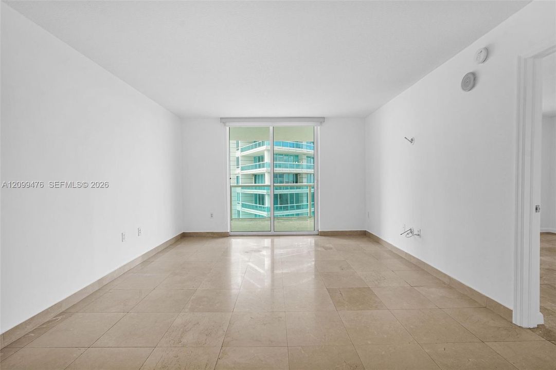 Interior space featuring stone-style tile flooring, floor-to-ceiling sliding glass doors, and a glass-paneled balcony