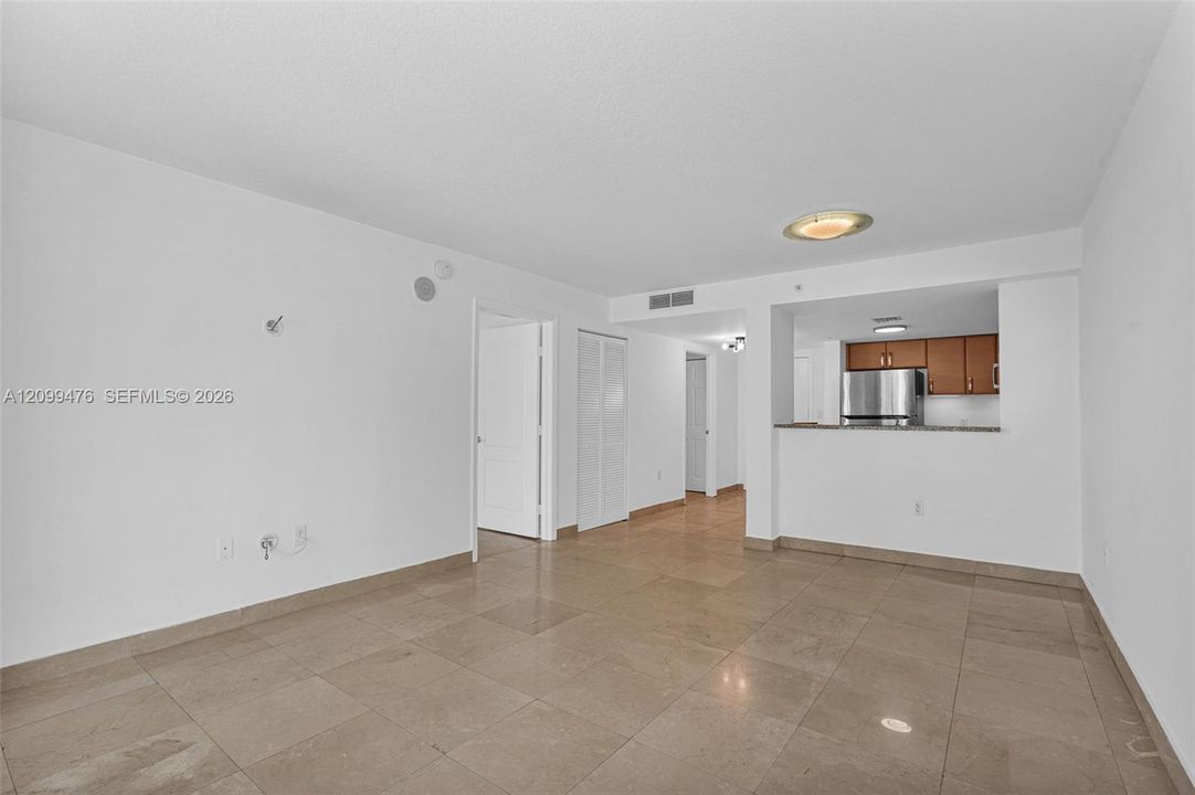 Open-concept room featuring large-format tile flooring, a kitchen pass-through counter, and stainless steel kitchen appliances