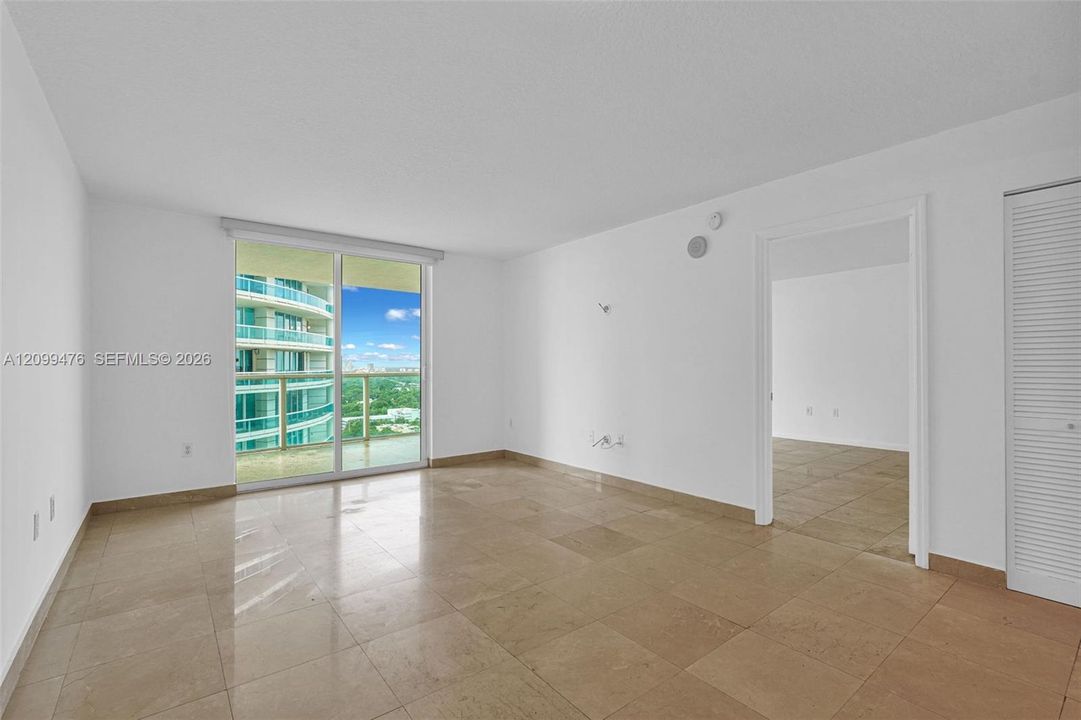 Open-concept interior featuring large-format tile flooring, floor-to-ceiling glass sliding doors, and louvered closet doors