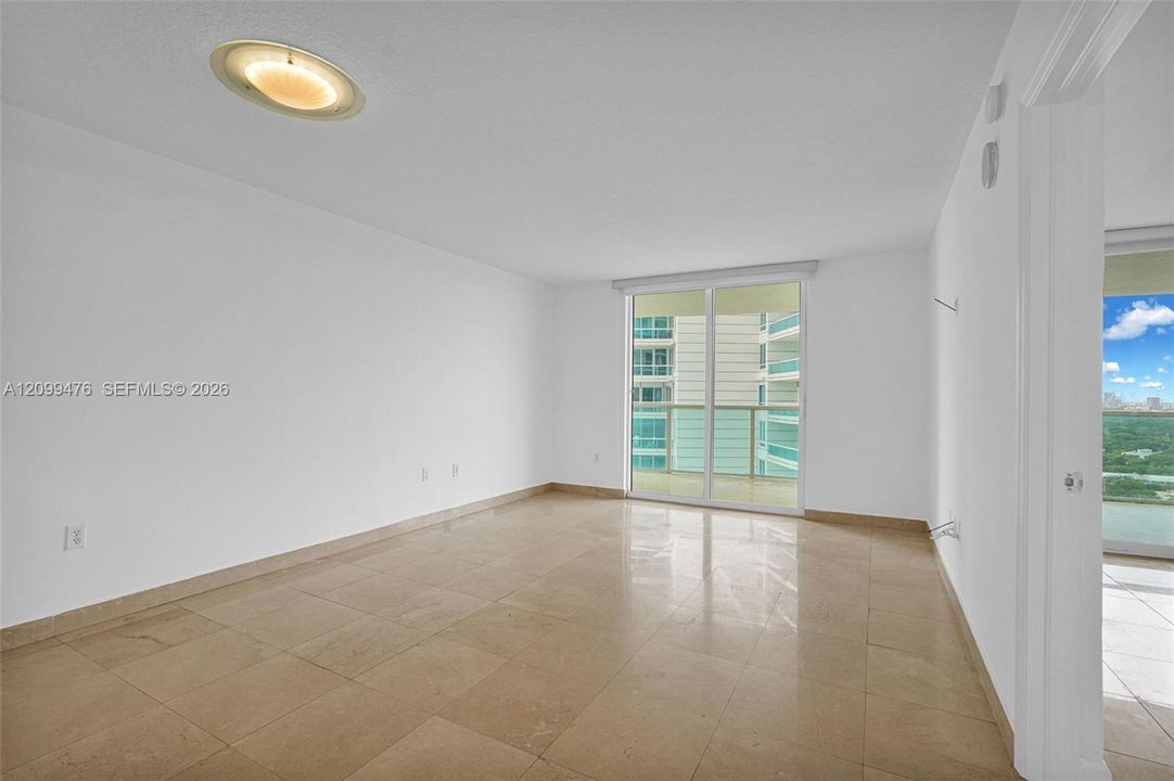 Interior space featuring large-format tile flooring, a flush-mount ceiling fixture, and a floor-to-ceiling glass sliding door providing access to an exterior balcony