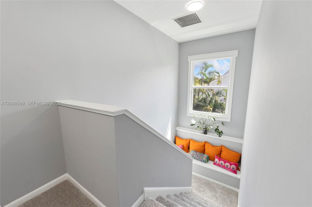 Neutral-toned interior featuring carpeting, a built-in bench seat with a display ledge, and a single-hung window with casing