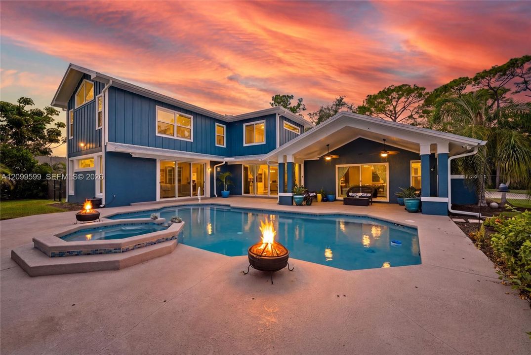 Exterior featuring vertical siding, concrete patio, swimming pool with integrated spa, and covered lanai