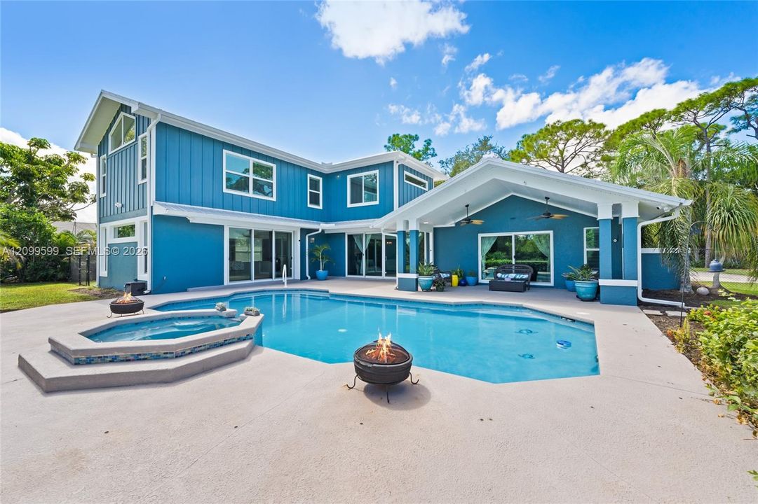 Board-and-batten siding exterior featuring a covered patio, swimming pool, integrated spa, and concrete deck
