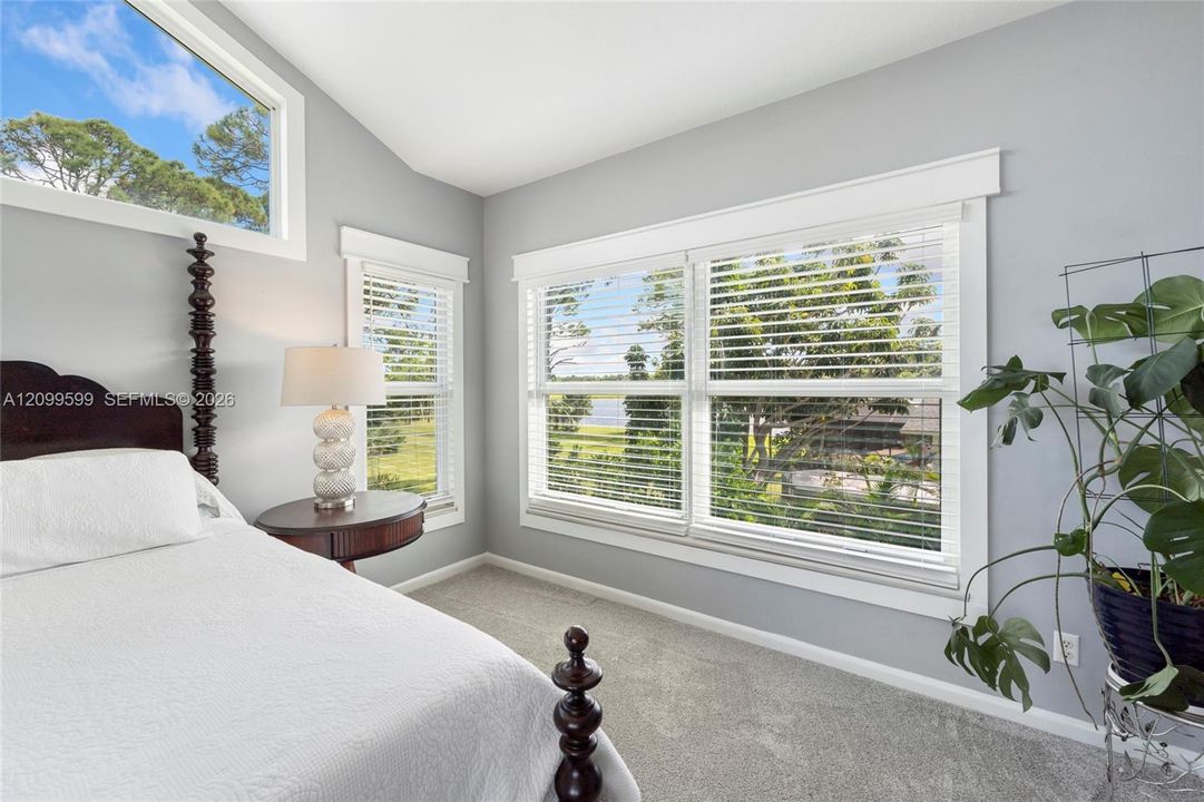 Vaulted ceiling, neutral wall tones, carpeted flooring, and oversized windows with white trim