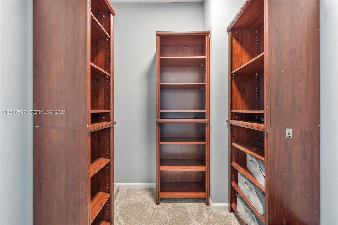 Built-in floor-to-ceiling wood-finish shelving units with adjustable shelving and integrated slide-out storage drawers