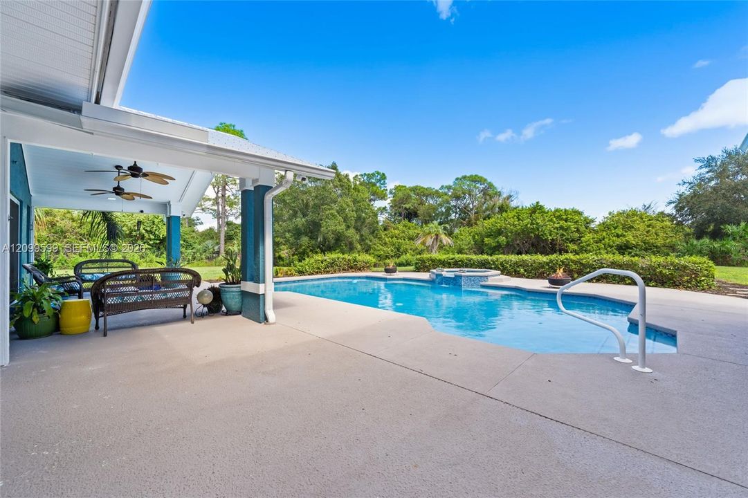 Covered patio with dual ceiling fans, concrete decking, in-ground swimming pool, and an integrated spa
