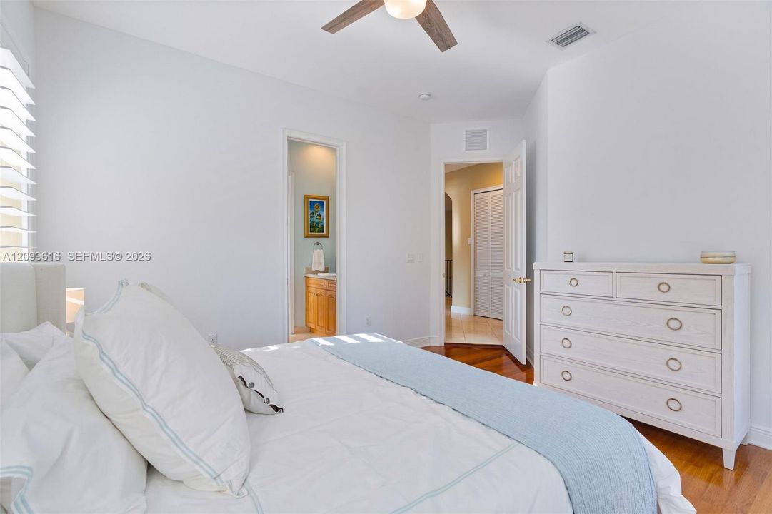 Bedroom featuring wood-finish flooring, ceiling fan with integrated lighting, and louvered closet doors