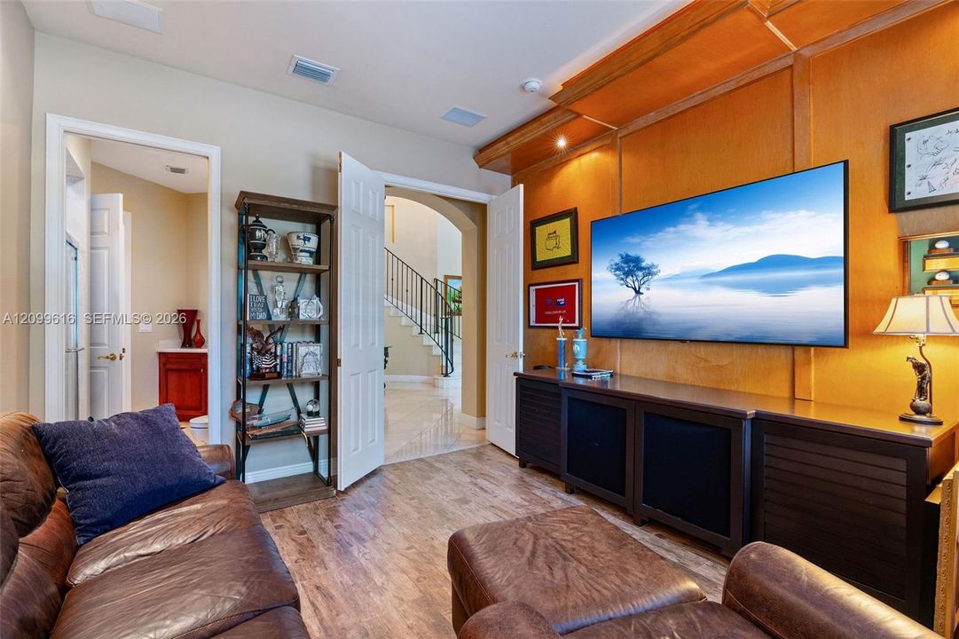 Wood-paneled accent wall with integrated cabinetry, wood-finish flooring, and arched doorway entry