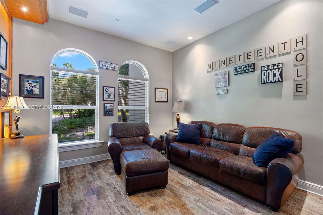 Room featuring high ceilings, wood-finish flooring, and two arched windows