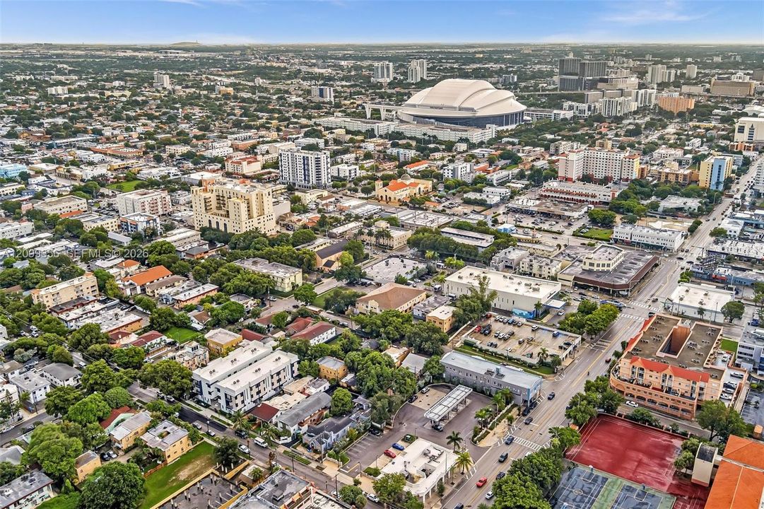Expansive urban landscape featuring diverse architectural styles, tree-lined streets, and a prominent stadium structure