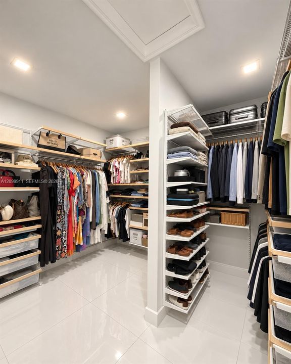 Walk-in closet featuring extensive built-in shelving, adjustable metal clothing rods, integrated drawer units, and light-reflecting tile flooring