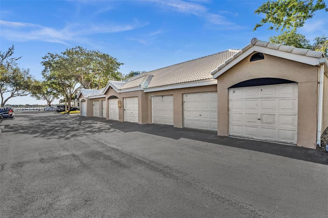 Multi-bay garage complex featuring a concrete tile roof, stucco exterior, and individual paneled garage doors